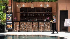 Zona de bar con piscina, taburetes y un barman.