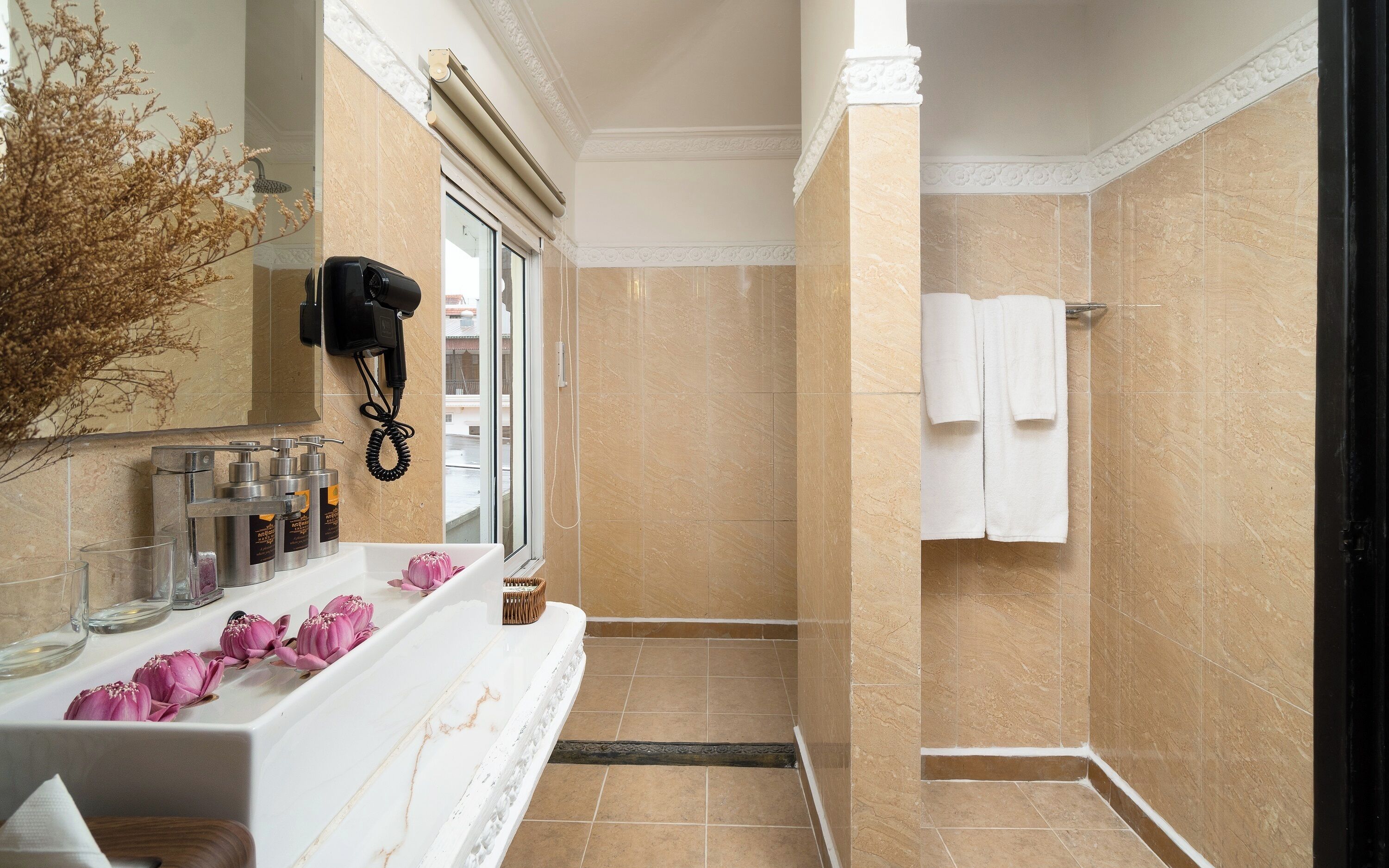 A bathroom with a marble vanity, a hairdryer, a towel rack, and a view of the outside.