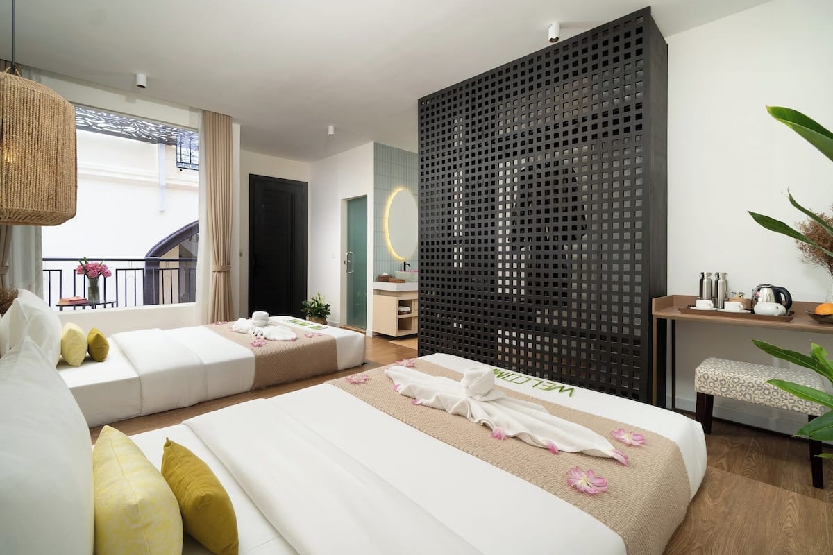 Una habitación de hotel moderna con dos camas, un balcón, un ventanal grande y suelo de madera.