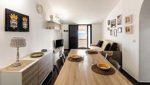 Zona pranzo moderna con tavolo in legno, sedie e televisore.