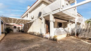Un edificio a due piani con un balcone, un patio coperto e un cortile con lastre di pietra.