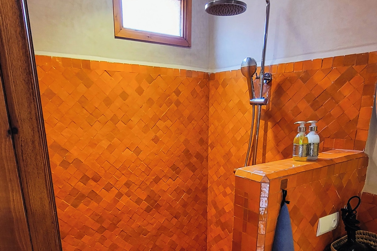 Un espacio de ducha con piso de baldosas, un cabezal de ducha y una ventana en la parte superior.