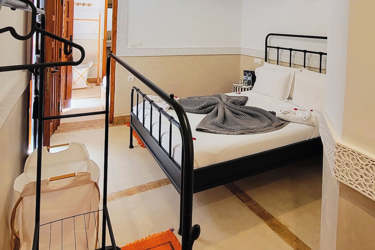 Un dormitorio con cama, lámpara colgante, armario y una escalera.