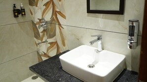 Une salle de bain avec un lavabo blanc, un miroir et une douche.