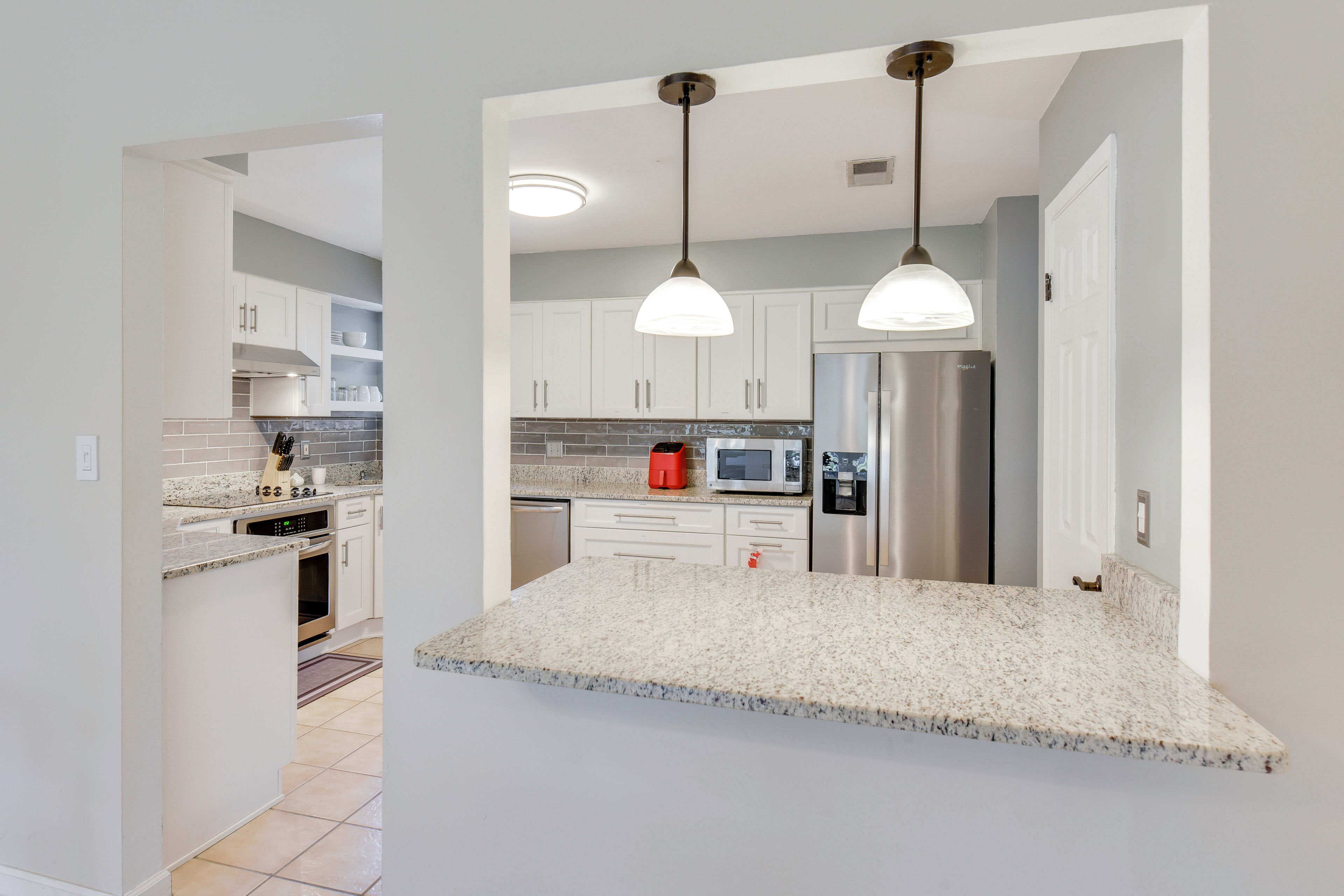 A modern kitchen with granite countertops, stainless steel appliances, and pendant lighting.