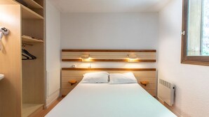 Un dormitorio con cama, mesitas de noche, un armario y una ventana.