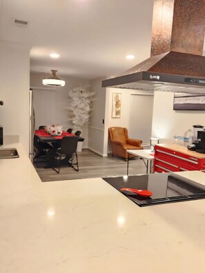 A modern kitchen with a marble countertop, a red storage unit, a ceiling fan, and a dining area with a white decorative wall. - Serene 3-bedroom house with AC in charming Columbus (Columbus)