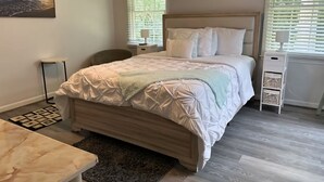 Ein Schlafzimmer mit Bett, Nachttischen, einem Sessel, einem Schreibtisch und einem Bild an der Wand.