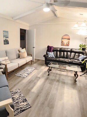 A living room with a sofa, a coffee table, a patterned rug, and a ceiling fan. - Serene 3-bedroom house with AC in charming Columbus (Columbus)