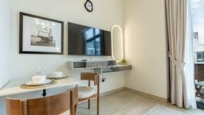 A modern dining area with a flat-screen TV, framed artwork, and a minimalist table setting. - Sophisticated Studio Getaway, Minutes Drive to Iconic Dubai Landmarks - Azizi Riviera 45, Al Merkadh (Dubai)