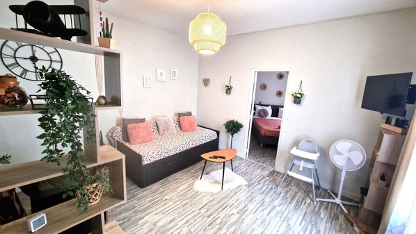 Un salon moderne avec un canapé, une petite table, un ventilateur et un téléviseur.