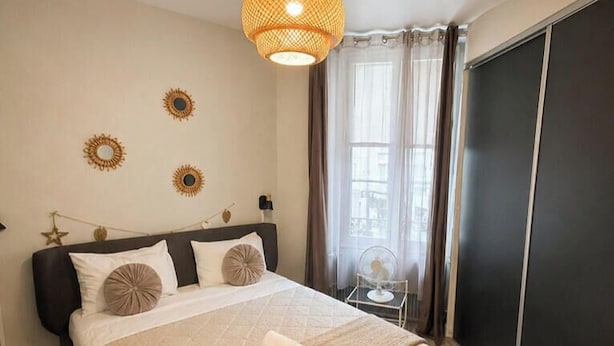 Un lit bien fait, avec une tête de lit, une table de chevet et une lampe suspendue.