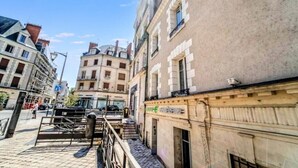 Une rue étroite bordée d’immeubles, une entrée fermée par un portail et une enseigne de magasin bien visible.