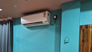 Ein Zimmer mit einem Bett, einer Klimaanlage, einer Holztür und einer Steckdose.