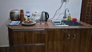 Eine Küche mit einer Granitabdeckung, einem Spülbecken, einem Wasserkocher, einer Kaffeemaschine und einem weiteren Wasserkocher auf der Arbeitsplatte.