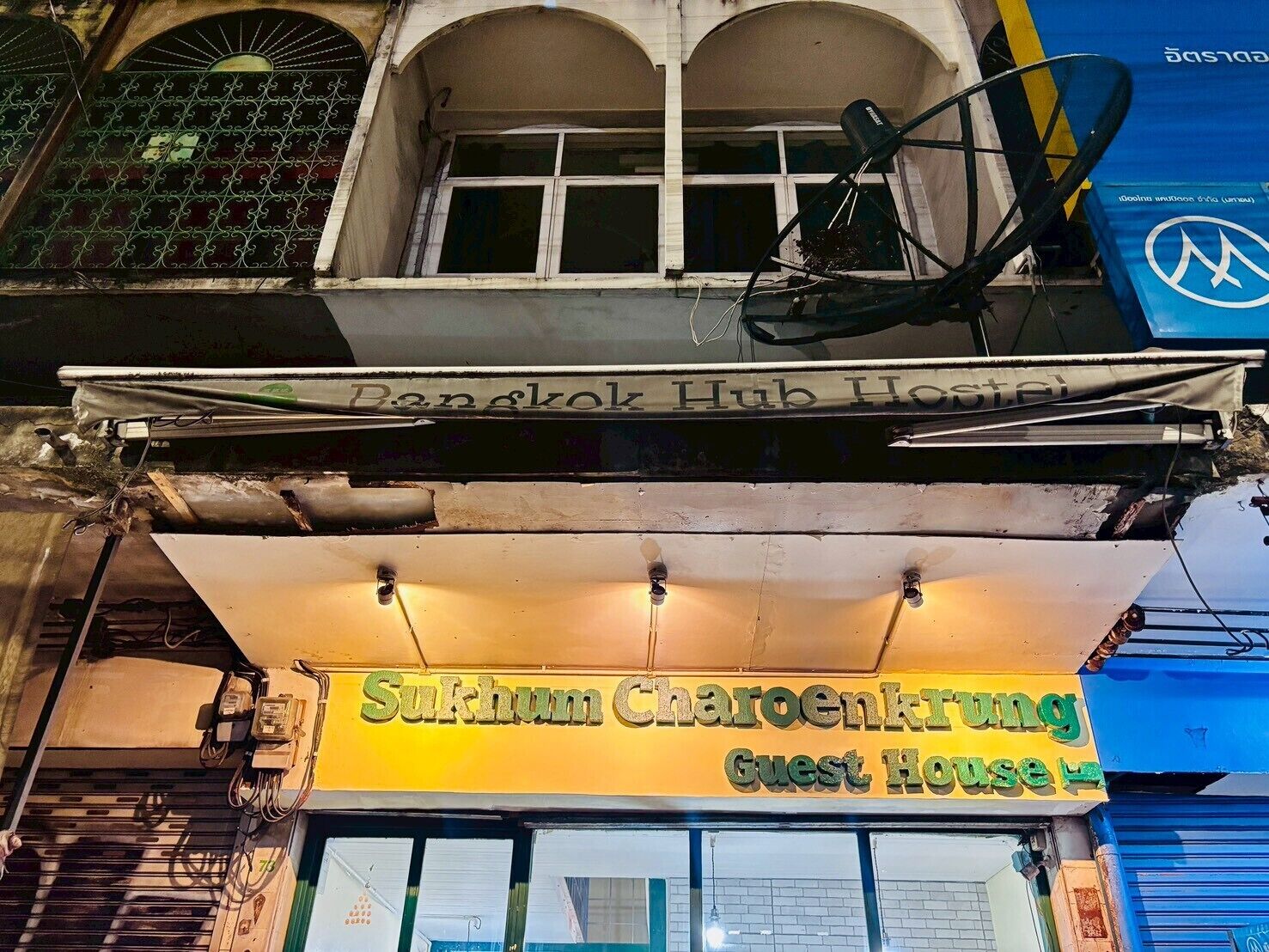 A building with a sign for 'Sukhum Charoenkrung Guest House' and a partially visible sign for 'Bangkok Hub Hotel.'