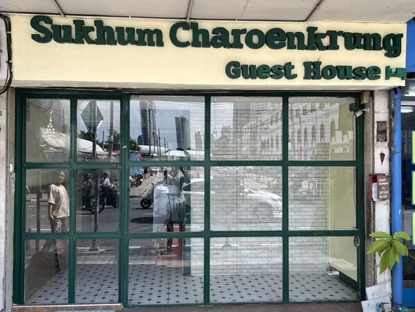 Ein Gebäude mit einem Schild, auf dem 'Sukhum Charoenkrung Guest House' steht.