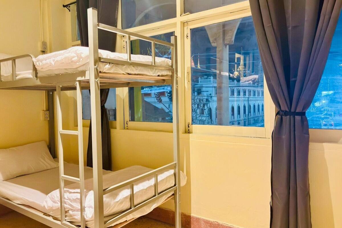 A bunk bed room with a window view of a cityscape.