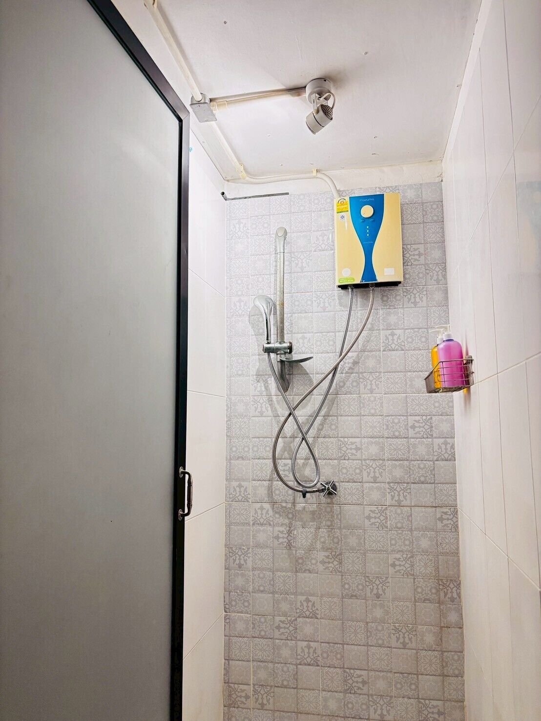 A shower with a handheld showerhead, a wall-mounted faucet, and a control panel.