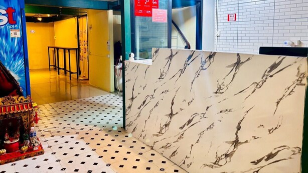 A hotel lobby with a marble reception desk, a yellow wall, and a blue door. - Sukhum Charoen Krung Tak-Sin guest house (Bangkok)