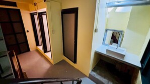 A hallway with a staircase, a door, and a window with a view of the outside. - Sukhum Charoen Krung Tak-Sin guest house (Bangkok)