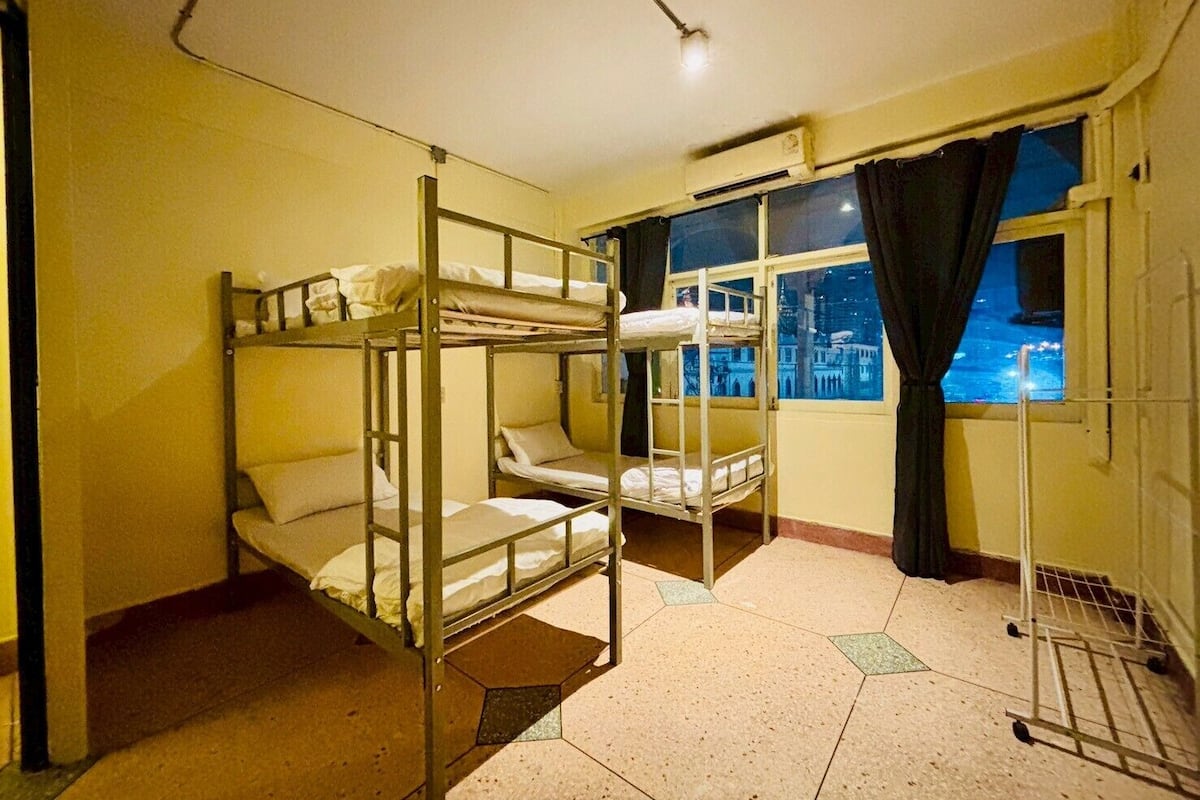 A bunk room with a window view of a cityscape at night.