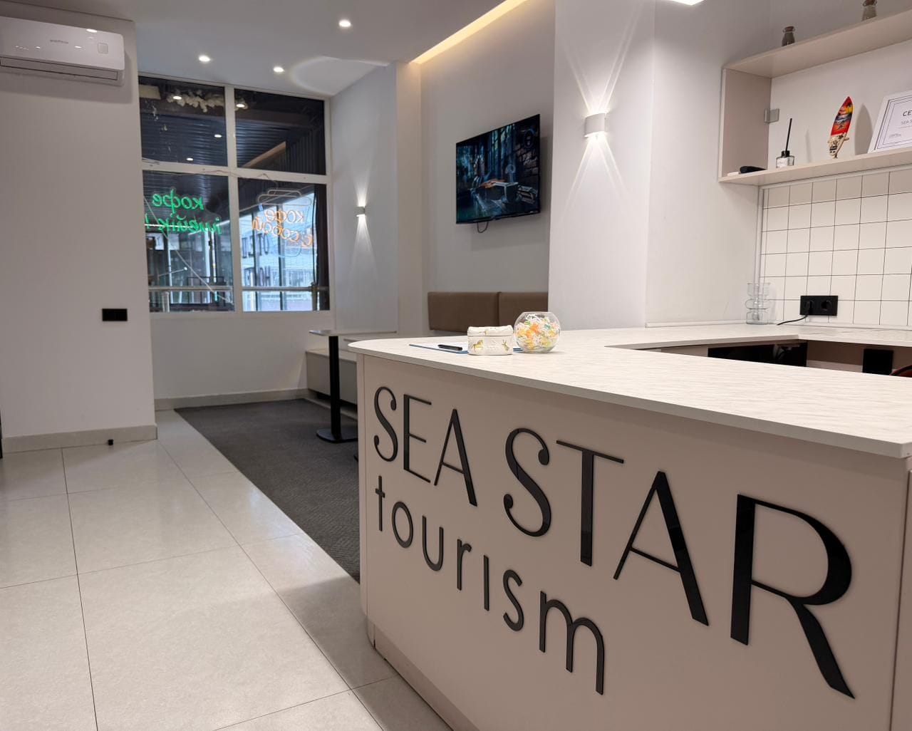 A reception area with a sign reading 'SEA STAR tourism' and a television mounted on the wall.