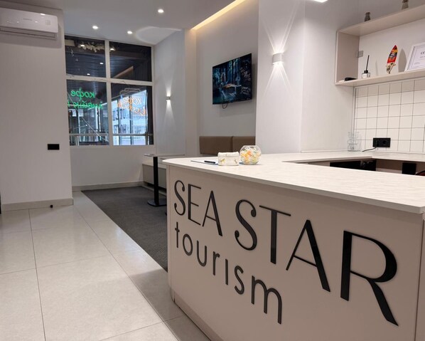 A reception area with a sign reading 'SEA STAR tourism' and a television mounted on the wall. - SeaStar Boutique Hotel (Almaty)
