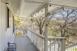 A covered porch with a bench, a clock, and a view of trees and hills. - Mtn-View Getaway w/ Game Room, 1 Mi to Kern River! (Wofford Heights)
