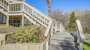 A wooden staircase leading up to a building with a white railing, surrounded by greenery and a mountain in the background. - Mtn-View Getaway w/ Game Room, 1 Mi to Kern River! (Wofford Heights)