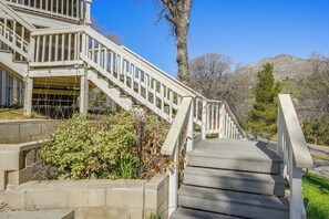 A wooden staircase leading up to a building with a white railing, surrounded by greenery and a mountain in the background. - Mtn-View Getaway w/ Game Room, 1 Mi to Kern River! (Wofford Heights)
