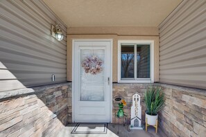 A front door with a welcome mat, a decorative wreath, a small welcome sign, and a potted plant.