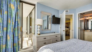 A bedroom with a bed, a dresser, a mirror, a television, and a sliding glass door leading to a balcony. - Oceanfront Myrtle Beach Getaway w/ Balcony (Myrtle Beach)