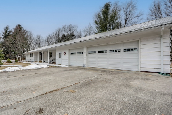 A single-story building with a garage, a porch, and a small front yard with snow.