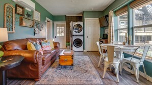 A living room with a brown leather couch, a wooden chest, and a dining area with white chairs. - 'Walnut Creek Retreat' 9 Mi to Decatur Town Square (Decatur)