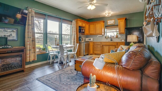 A living room with a leather sofa, a dining table with chairs, a fireplace, and a kitchen area with wooden cabinets and appliances. - 'Walnut Creek Retreat' 9 Mi to Decatur Town Square (Decatur)