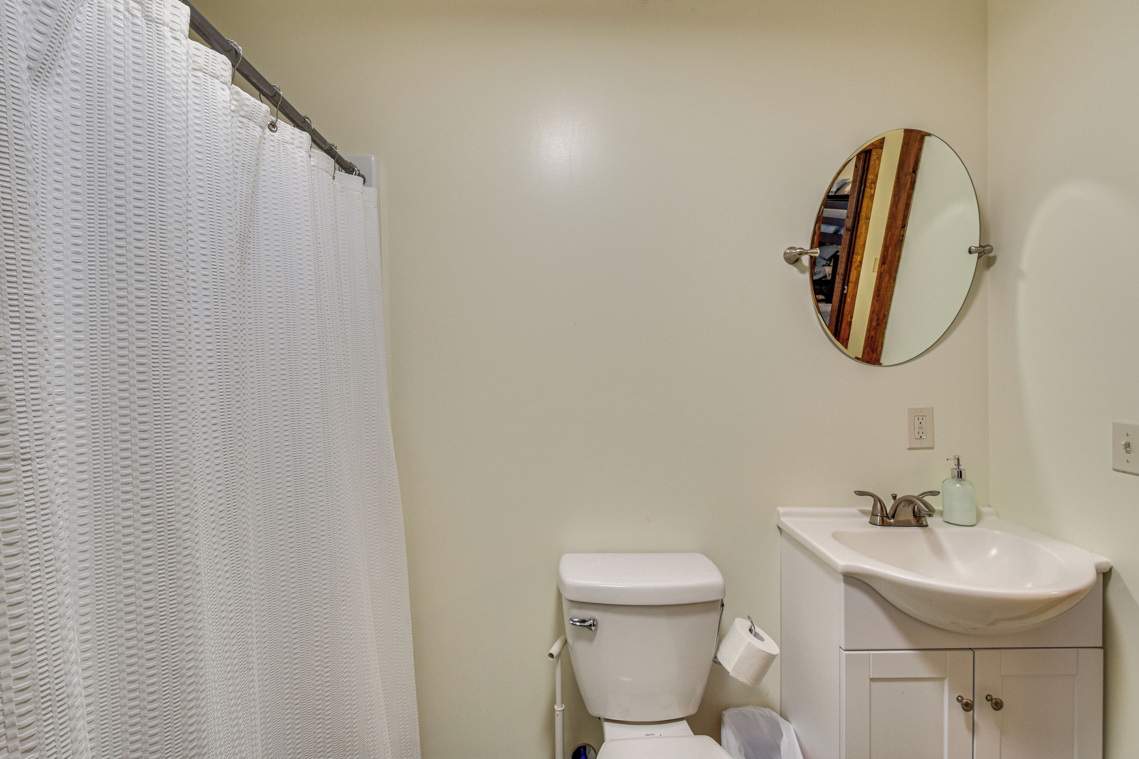 Un baño con inodoro, lavamanos y espejo.
