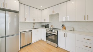 Eine moderne Küche mit weißen Schränken, Edelstahlgeräten und Holzboden.