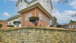 Ein zweigeschossiges Haus mit einer Steinmauer, einem Backsteinsschornstein und einem kleinen Baum auf dem Dach.