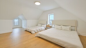Ein geräumiges Schlafzimmer im Dachgeschoss mit zwei Betten, Holzdielenboden und schrägverdeckter Decke.