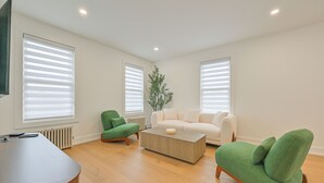 Ein modernes Wohnzimmer mit einer Couch, einem grünen Sessel, einem Couchtisch und einem Fernseher.