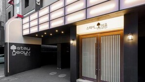 A building with a modern facade, a sign for 'stay geoyu,' and a traditional wooden door. - Hotel Stay Yeoyu (Seoul)