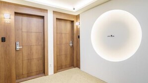 A hotel room with two wooden doors, numbered 306, and a circular light fixture on the wall. - Hotel Stay Yeoyu (Seoul)