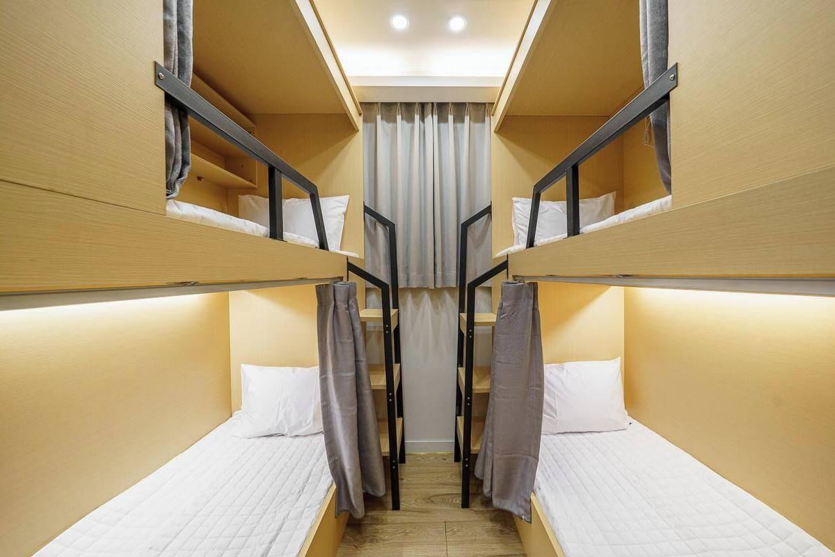 Une chambre avec un lit superposé, une porte centrale, des murs en bois et un luminaire au plafond.