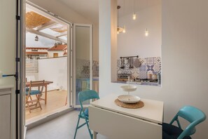 A modern kitchen with a white countertop, blue chairs, and a dining table. - Marinella Seafront (Avola)
