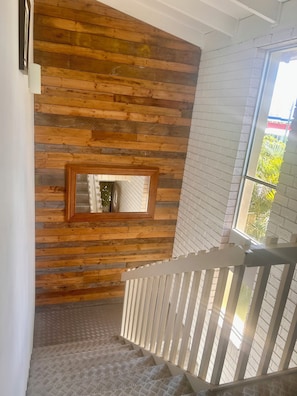 A staircase with a wooden wall and a metal railing.