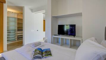 A hotel room with a bed, a TV on a stand, a bookshelf, and a walk-in closet.