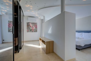 A modern hotel room with a bed, a wooden bench, and artwork on the walls.