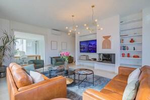 A modern living room with leather sofas, a coffee table, a TV, and a bookshelf. - Lugano Lake View Villa w. Private Pool (Lugano)