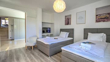 Ein modernes Hotelzimmer mit Bett, Nachttisch, Sessel und Schreibtisch mit Computer.